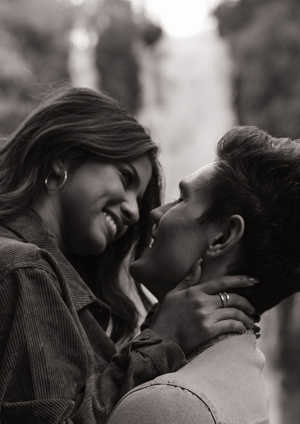 Black and white photo of couple smiling at each other during engagement photos