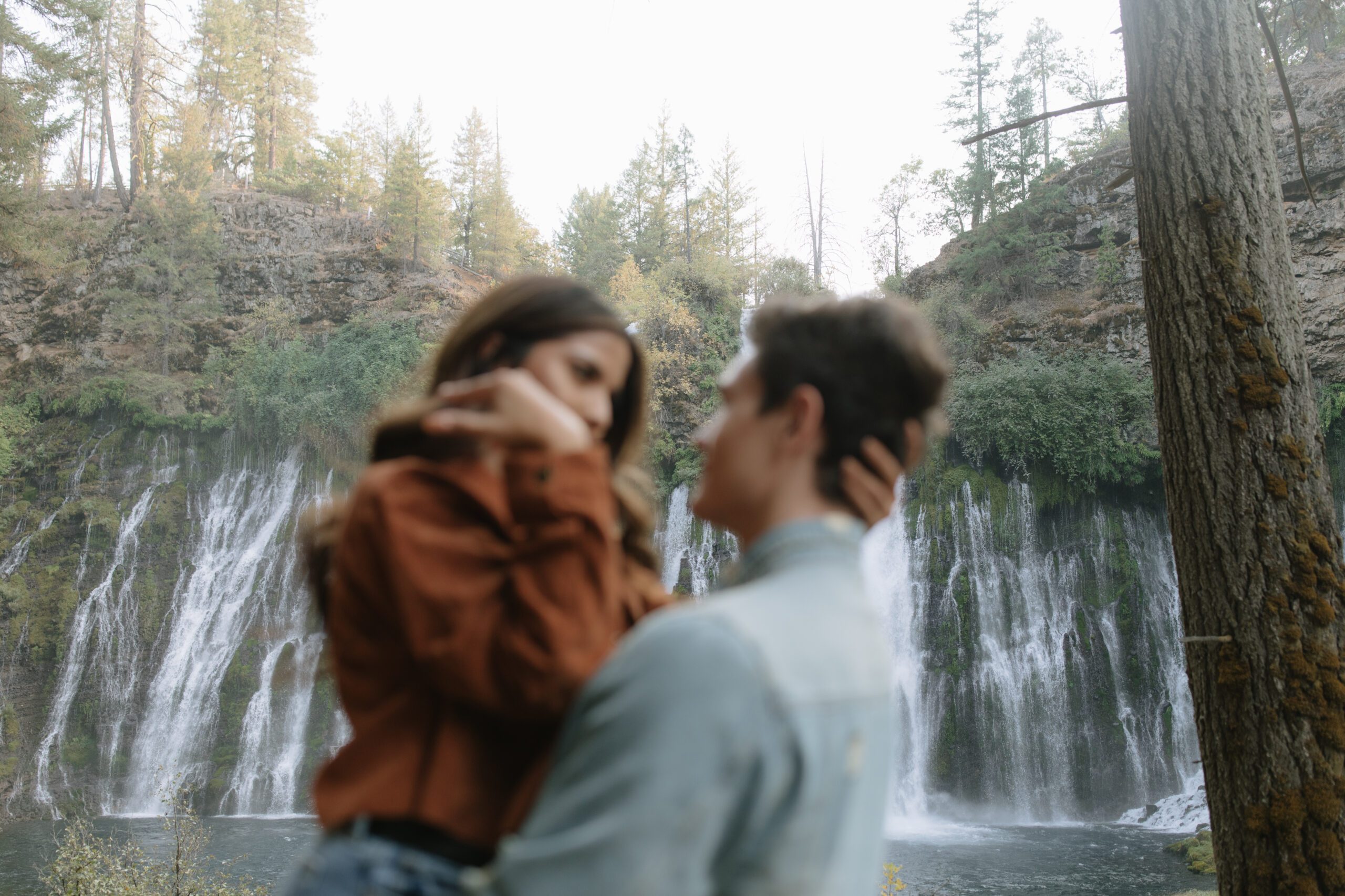 Blurry photo of couple looking at each other in front of waterfalls at burney falls