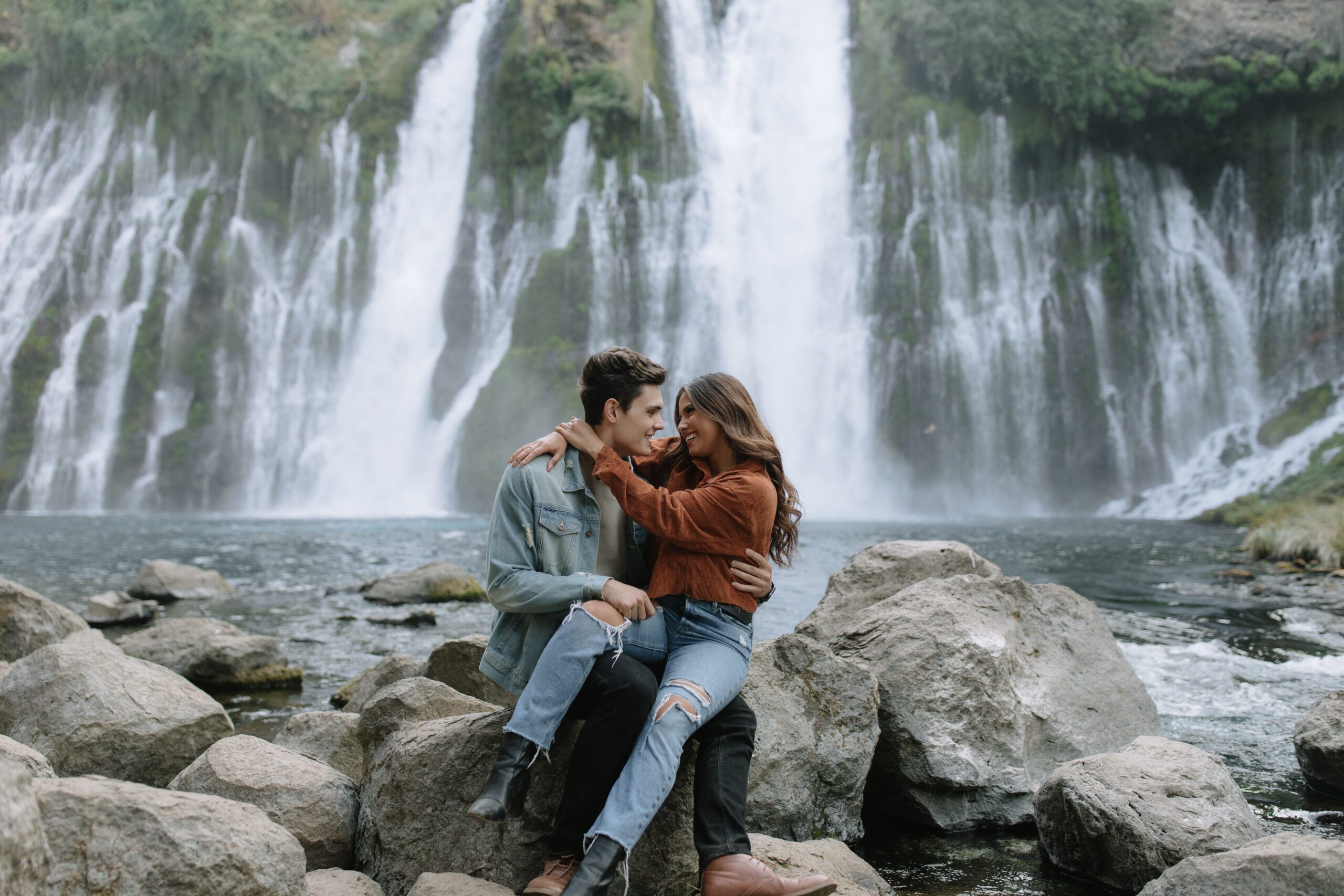 Couple sitting in front of burney falls for their engagement photoshoot