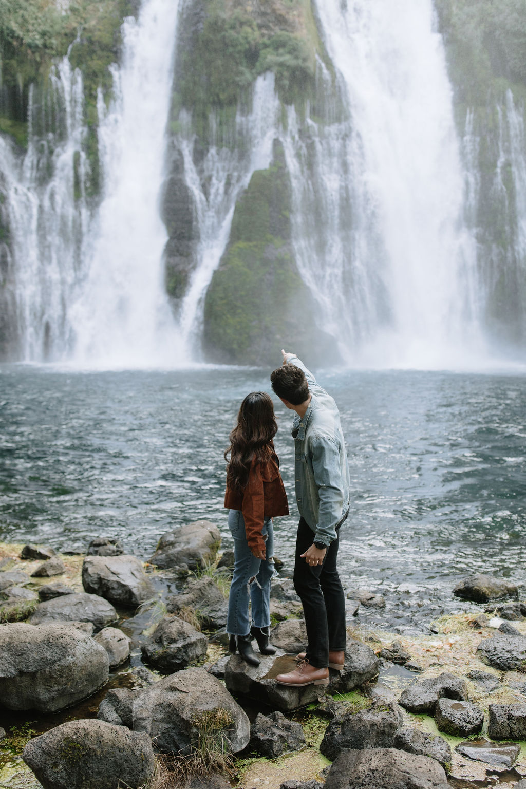 Engagement photos at Burney Falls with man pointing towards the waterfalls