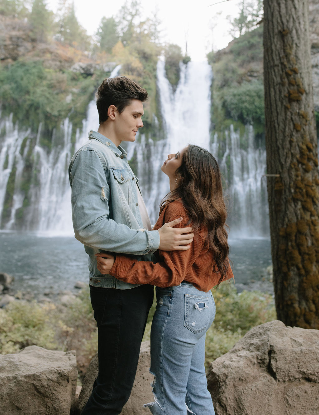 Couple looking at each other in front of Burney Falls waterfalls