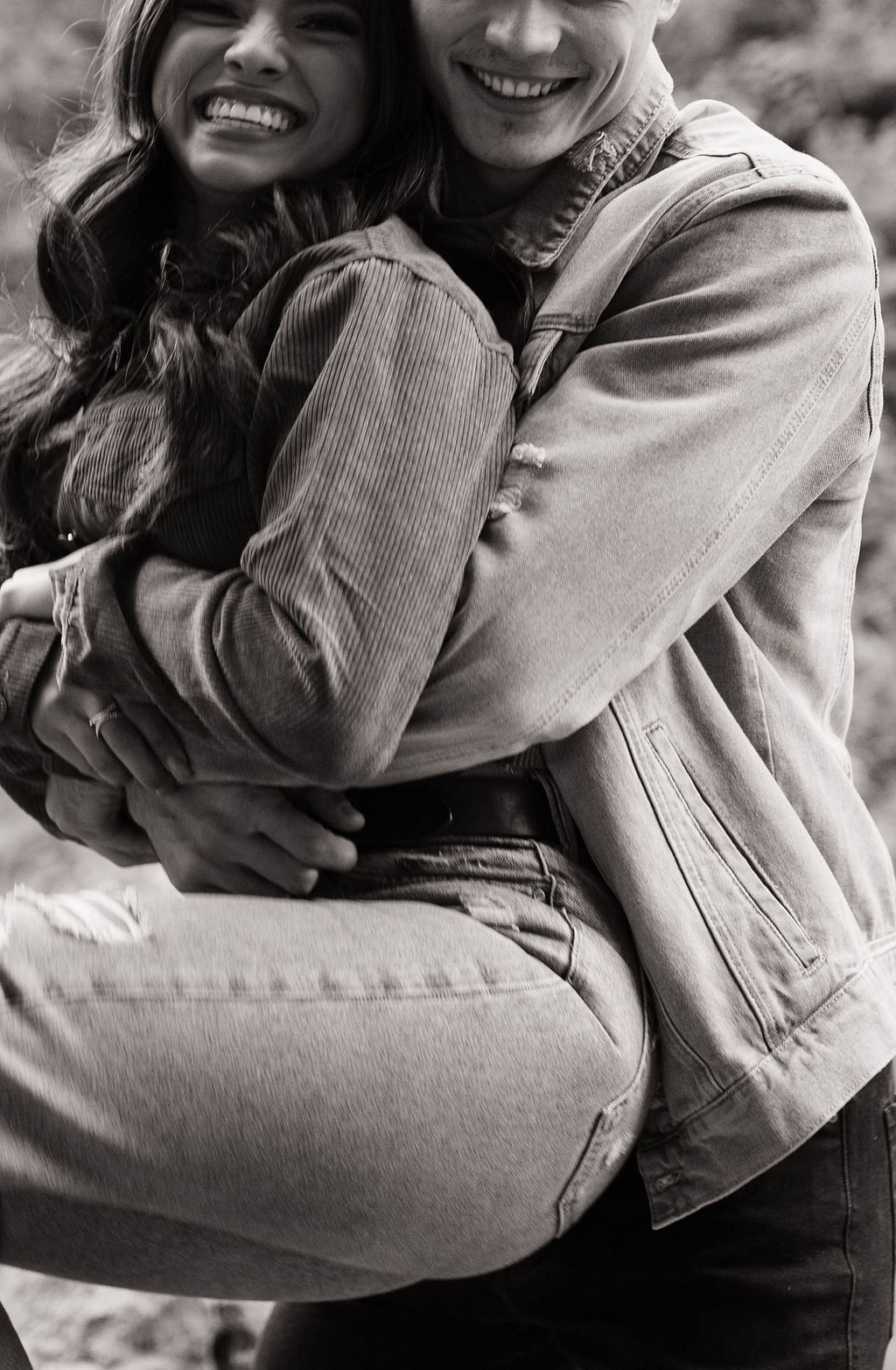 Black and white photo of couple laughing while man holds his fiancee during engagement photoshoot