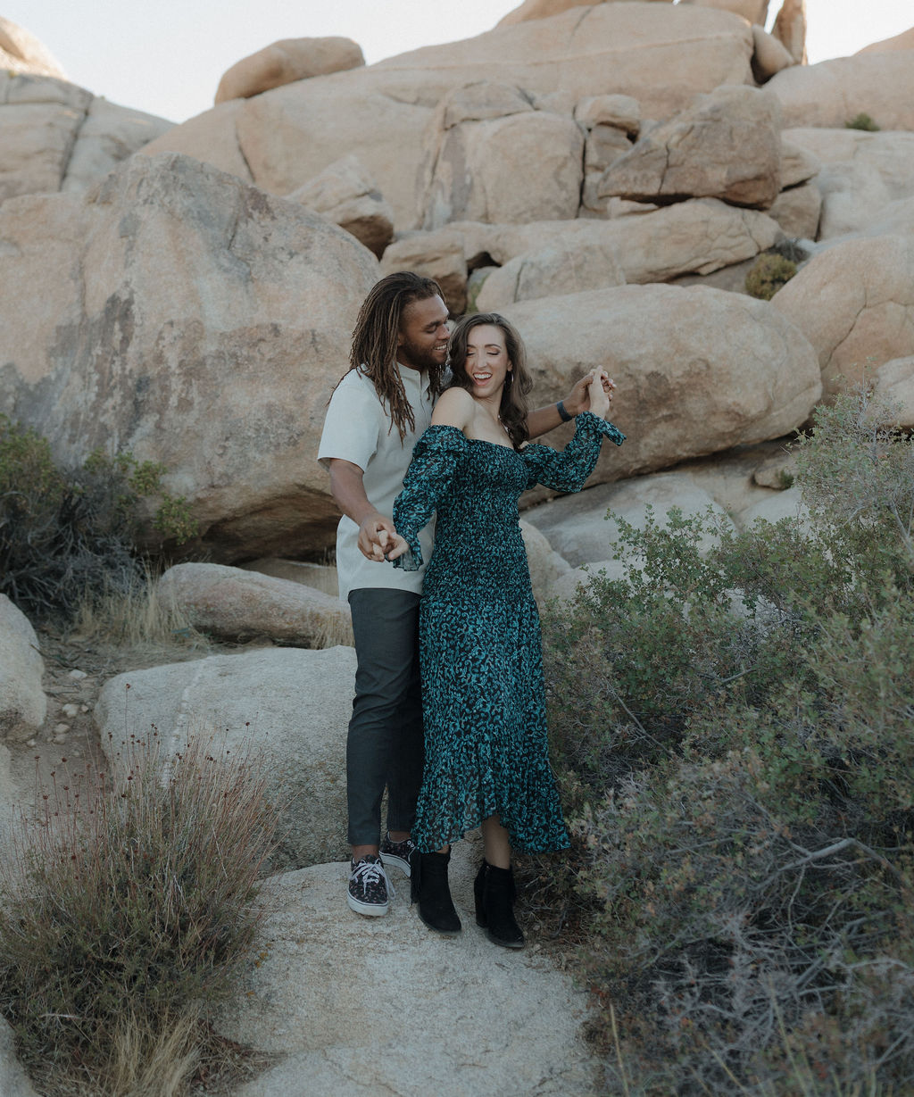 A couple posing for Joshua tree engagement photos in front of a rock formation