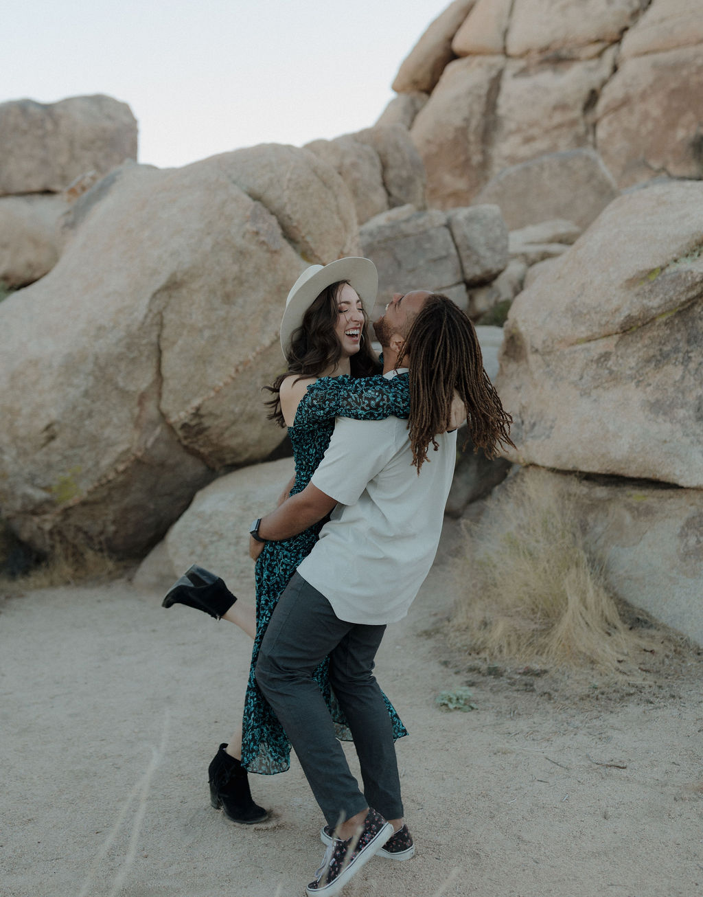 A man picking up his fiancee during a Joshua tree photoshoot