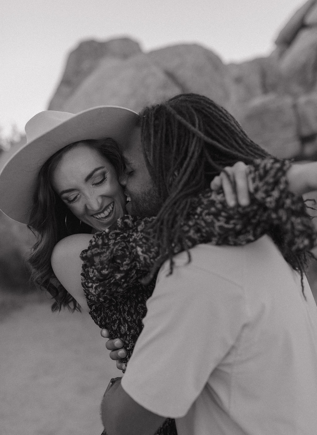 A man kissing his fiancee on the cheek during a Joshua tree photoshoot