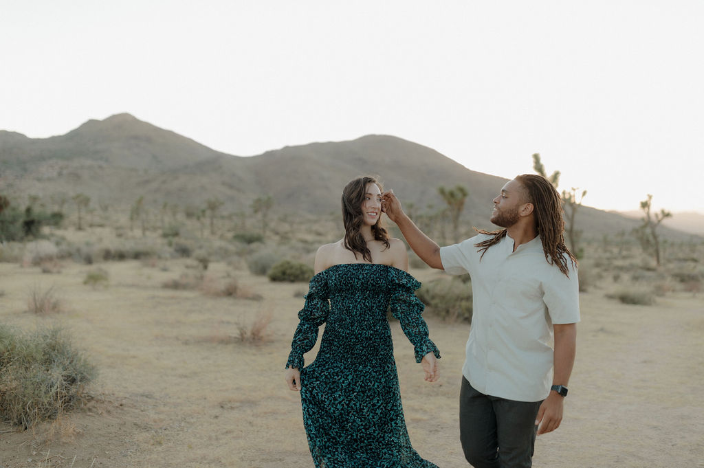 A man fixing his fiancee's hair during a Joshua tree photoshoot
