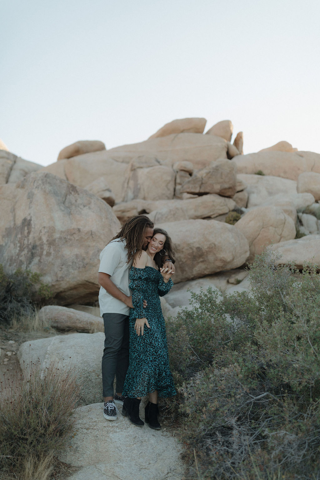A couple posing for Joshua tree engagement photos in front of a rock formation
