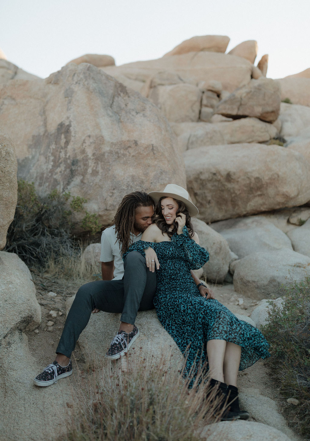 A man and his fiancee posing for a Joshua Tree photoshoot sitting on rocks