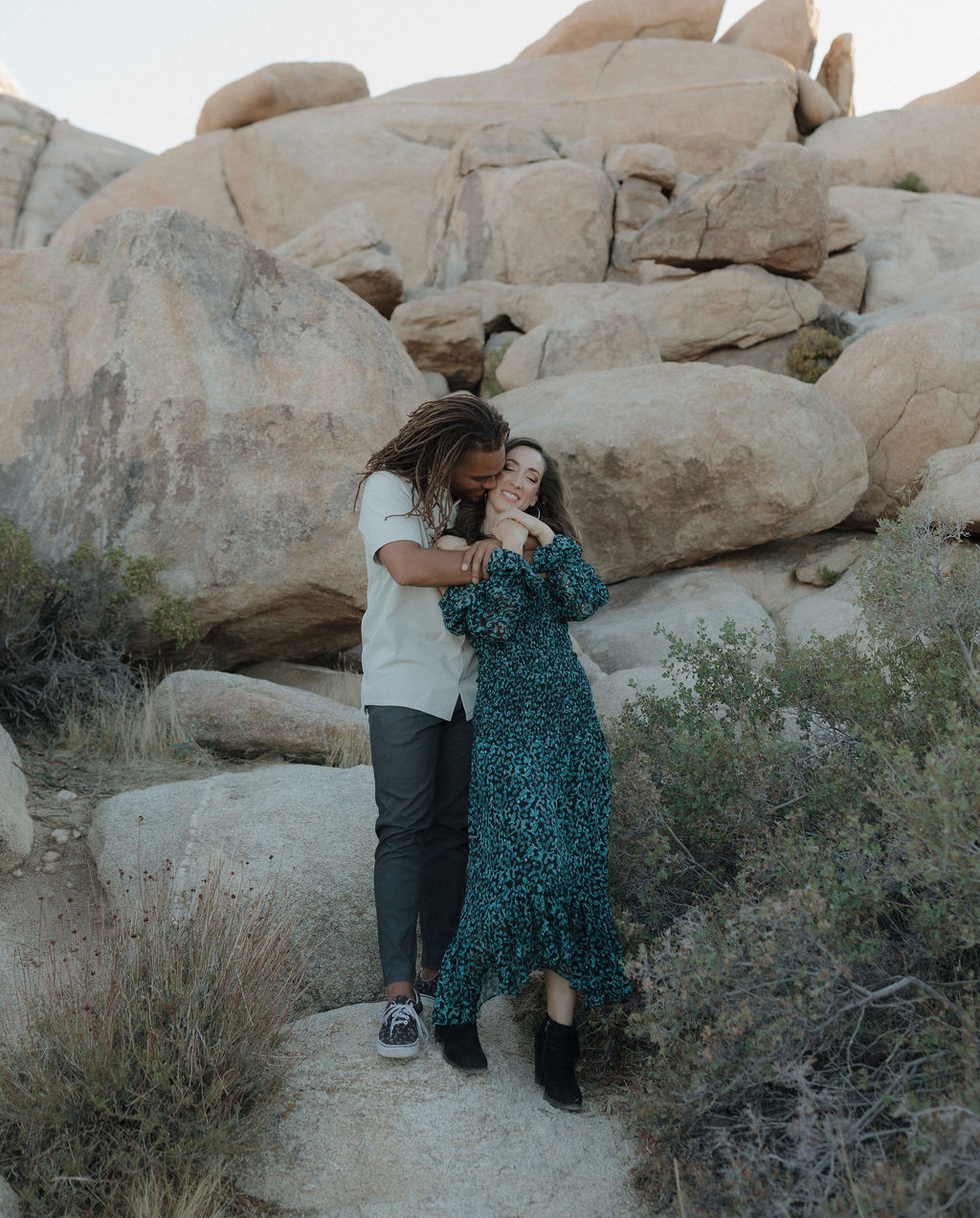 A couple posing for Joshua tree engagement photos in front of a rock formation