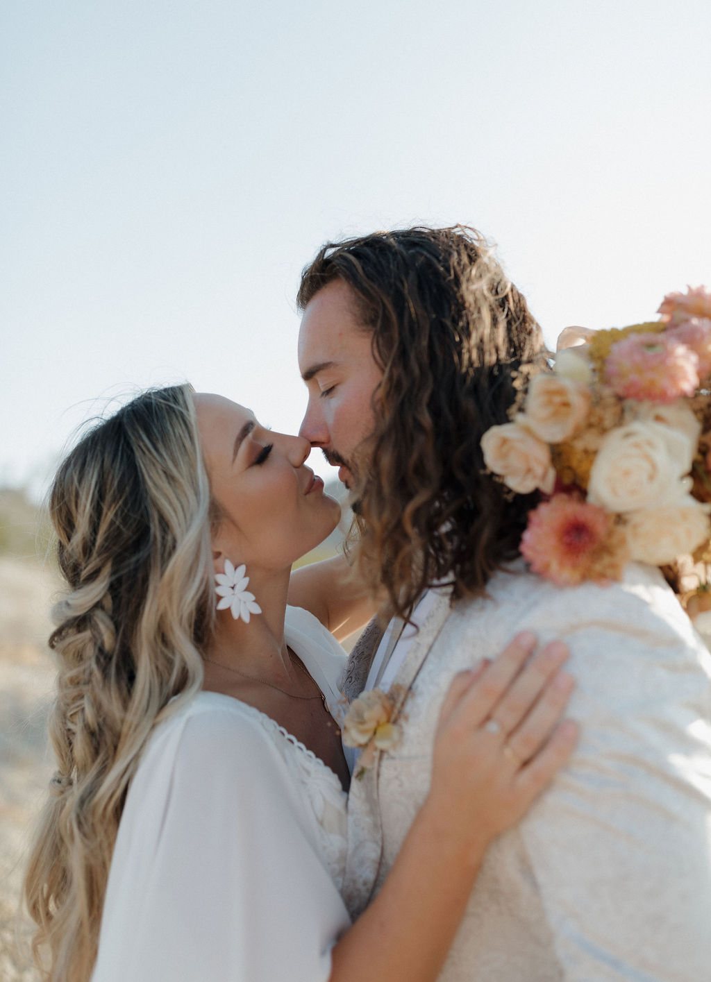 A bride and groom leaning in for a kiss at their boho wedding