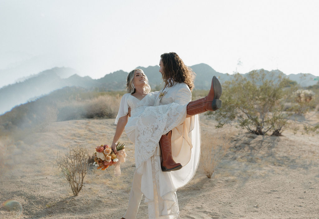 A groom holding a bride at a boho wedding