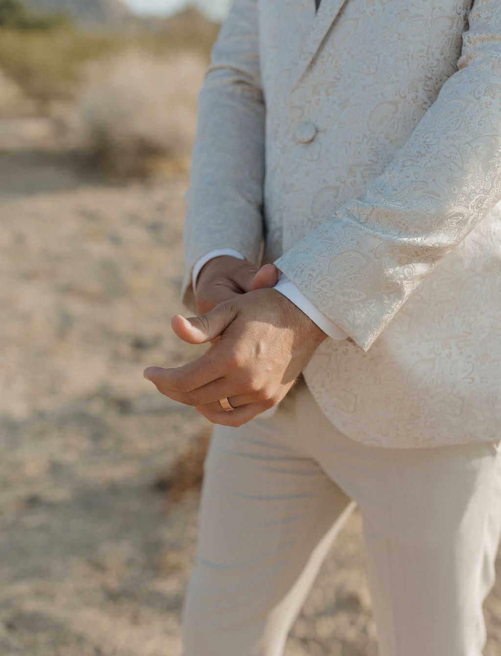 A groom buttoning the arm on a jacquard wedding suit