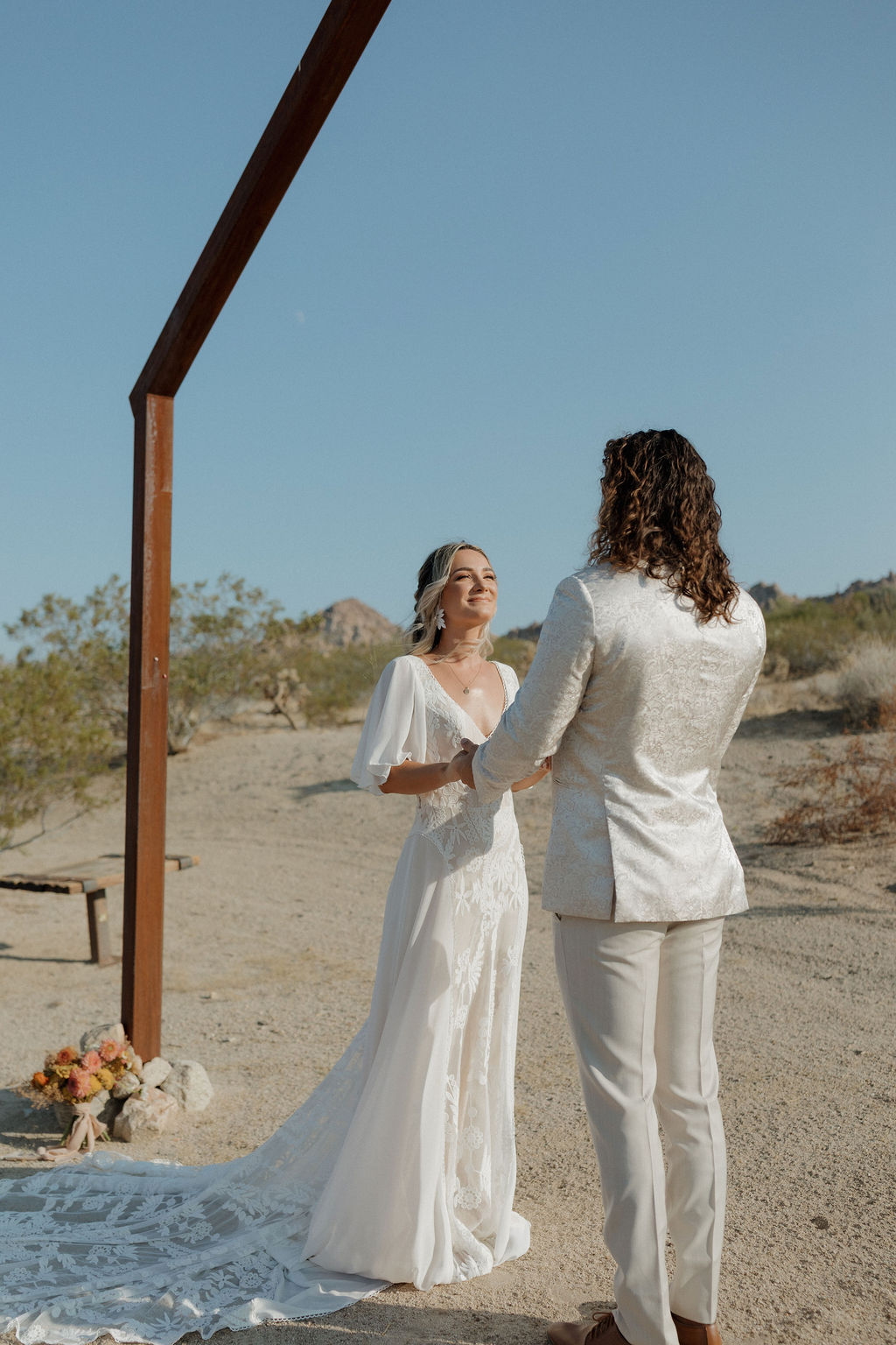 A bride and groom under a boho wedding arch