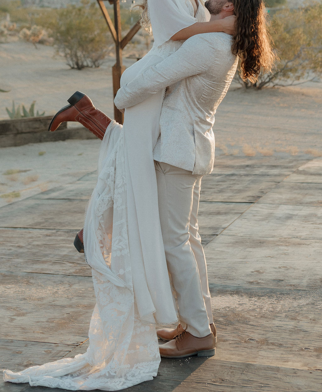 A groom holding a bride at a Joshua tree wedding