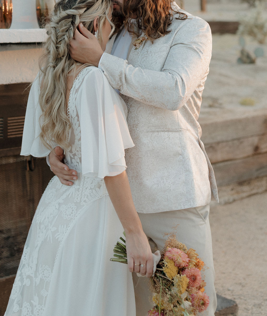 An editorial wedding photo of a groom kissing a bride on the head