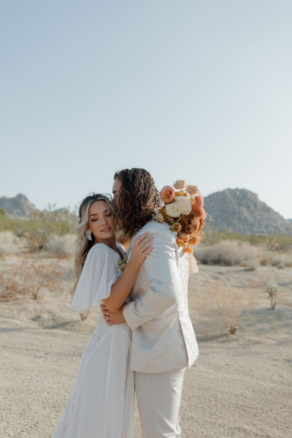 A bride and groom posing for photos at a boho wedding