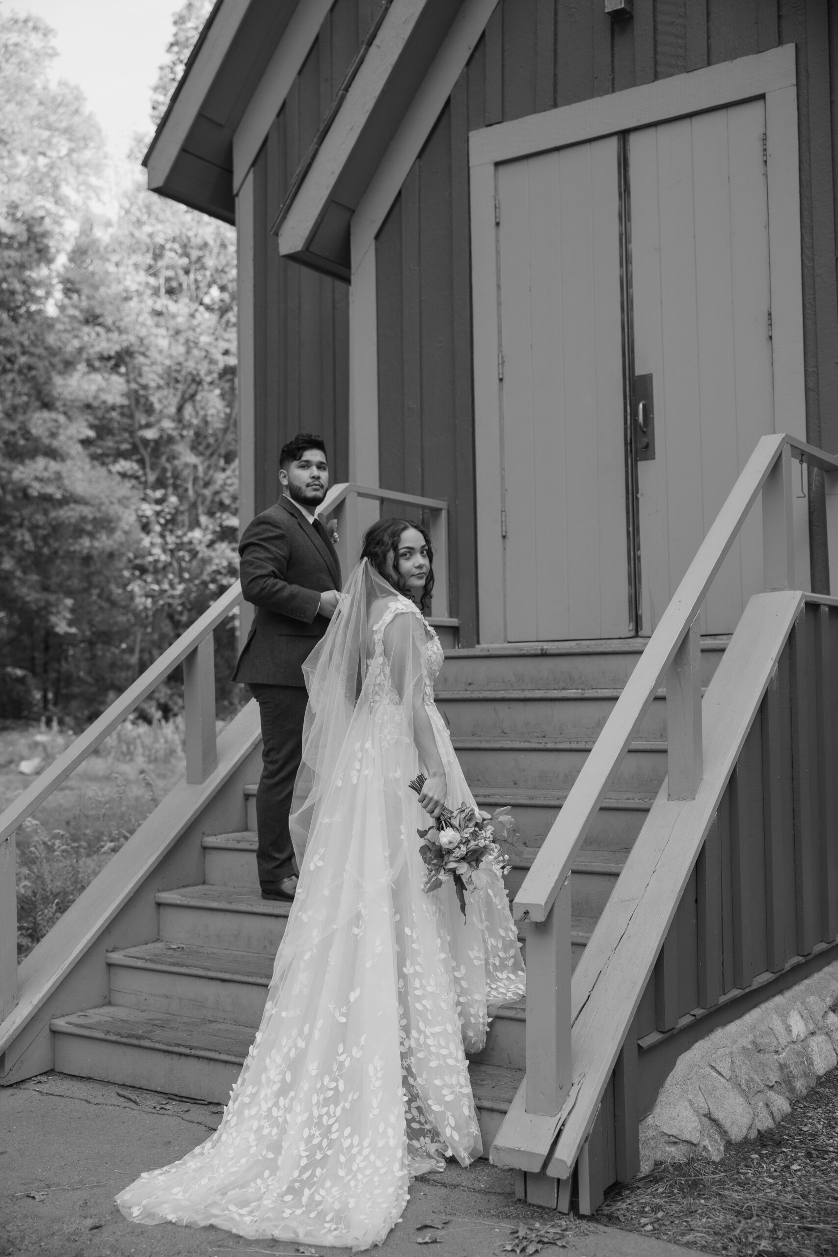Black and white wedding photo of bride and groom walking  up to Yosemite National Park Chapel