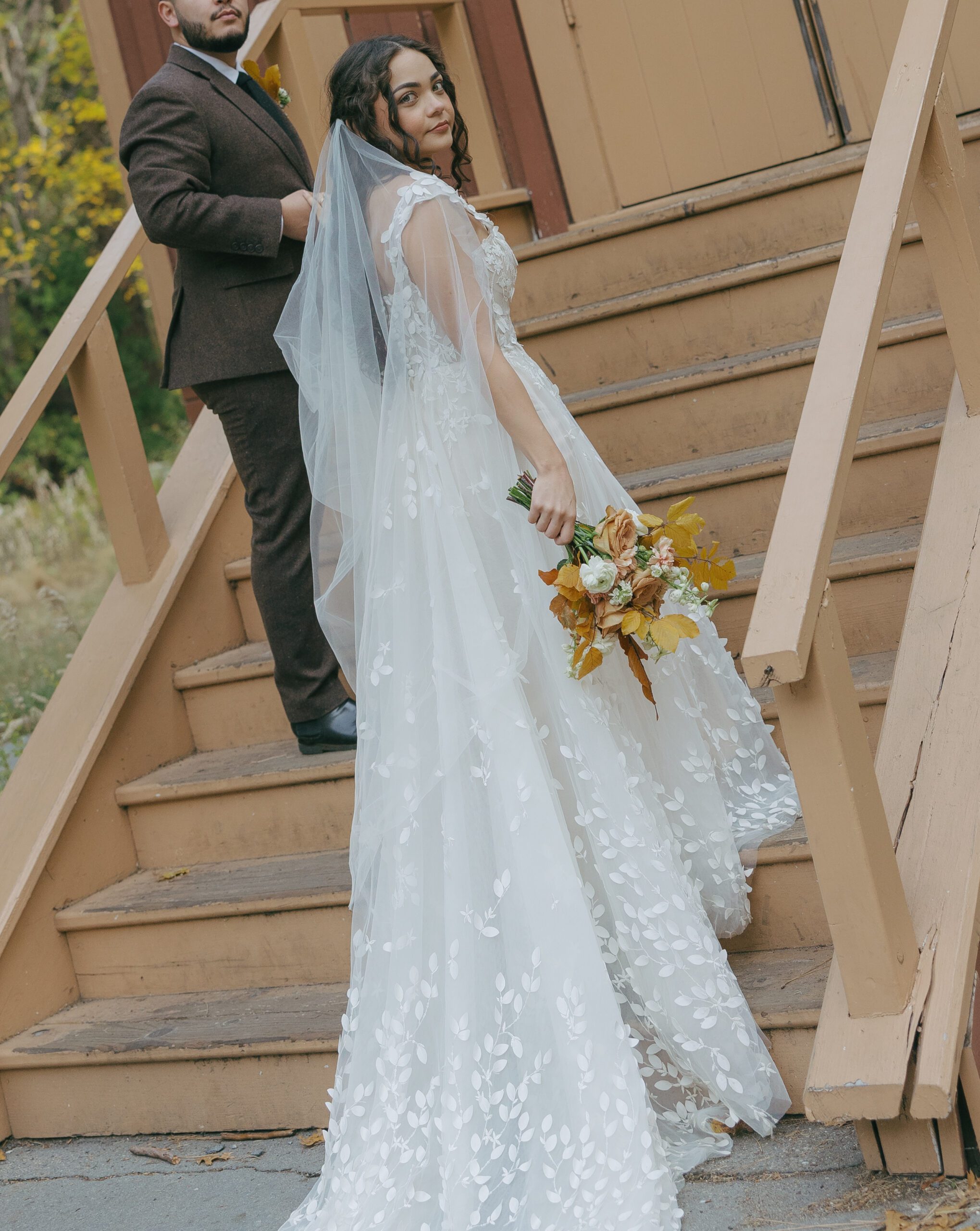 Bride and groom walking up chapel steps at Yosemite elopement with wedding dress train trailing down the stairs
