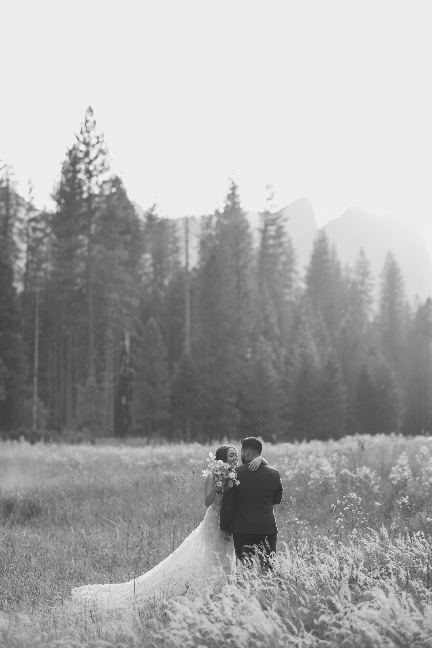 Bride and groom photo in a field with light hitting behind them 