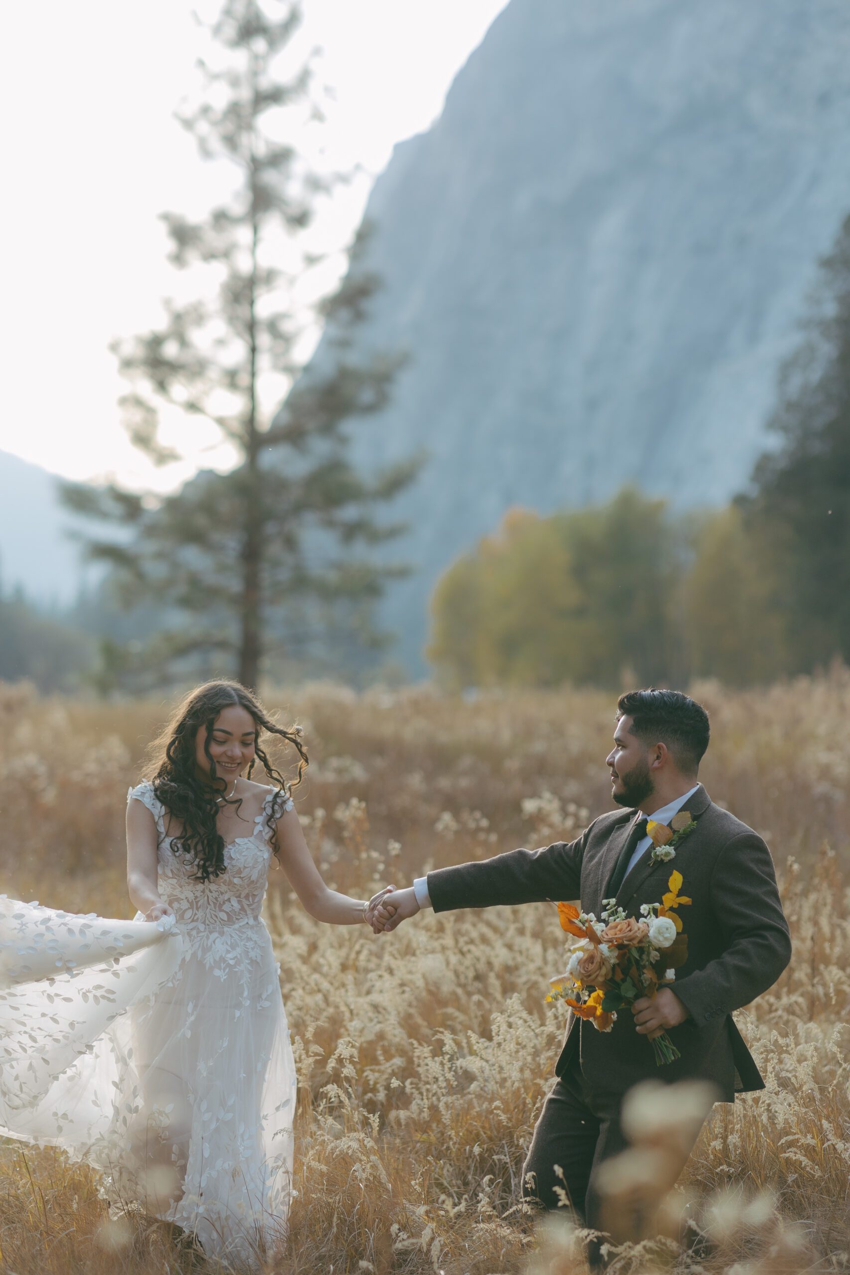 Bride and groom photo running through field holding hands at Yosemite wedding