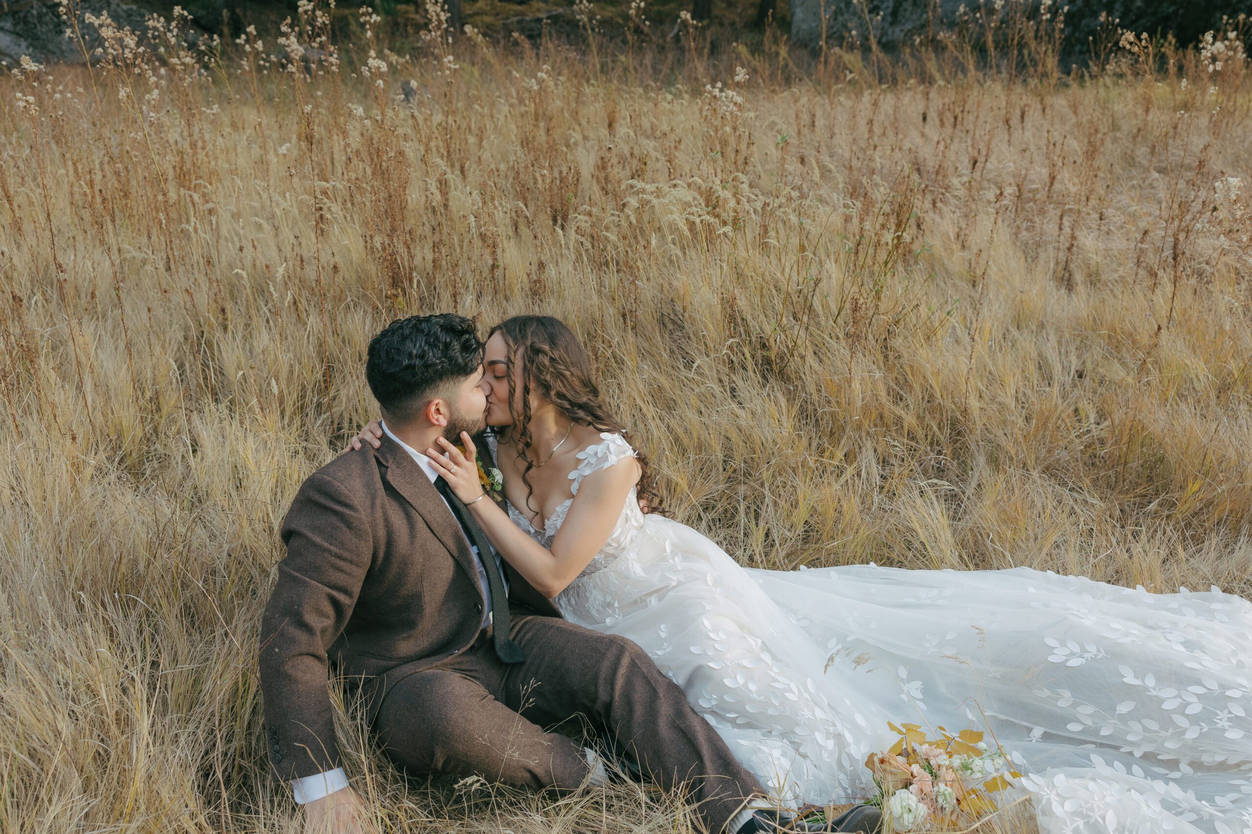 Bride and groom laying in a grassy field for photos at Yosemite Park elopement