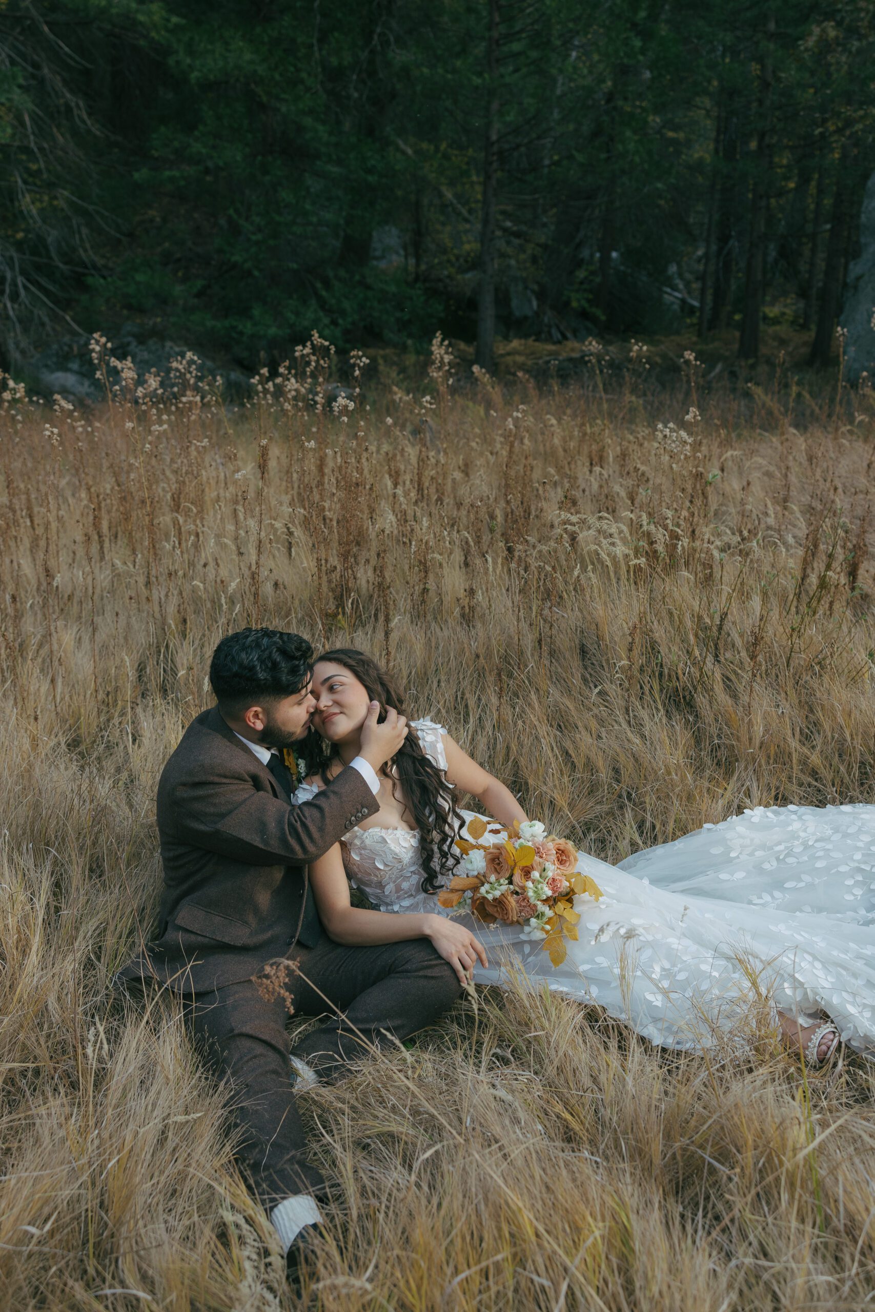 Bride and groom sitting in a field at Yosemite national park elopement
