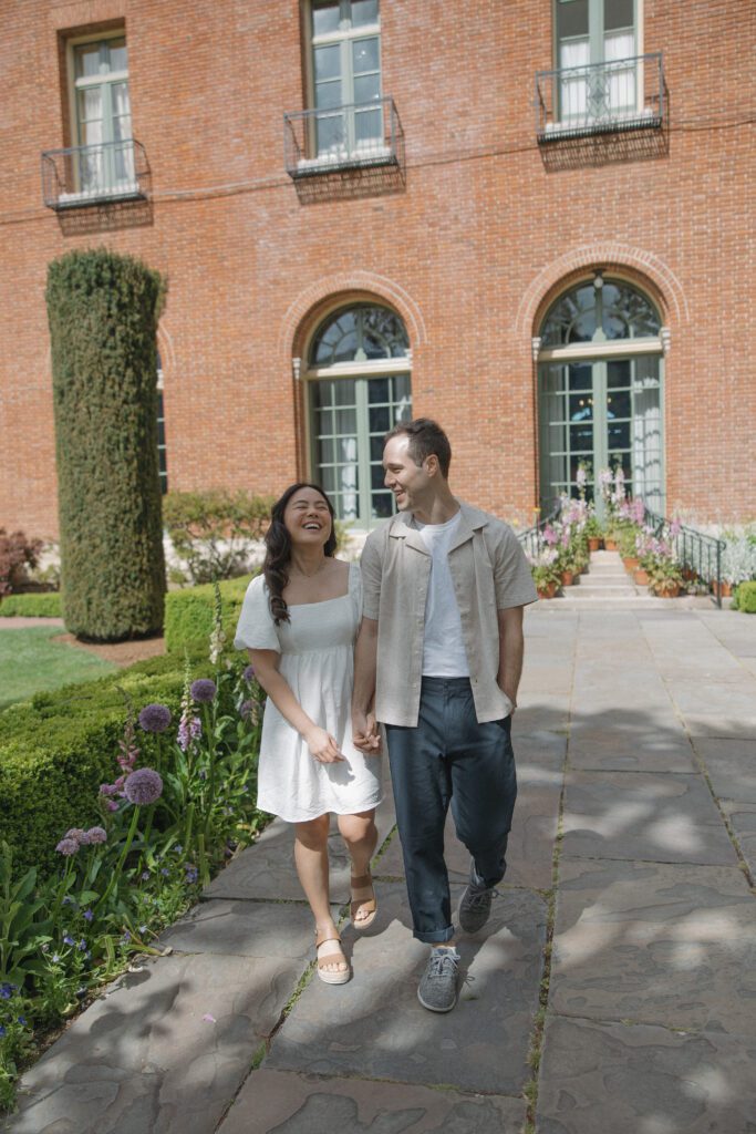Couple laughing walking through gardens at Bay Area engagement photoshoot