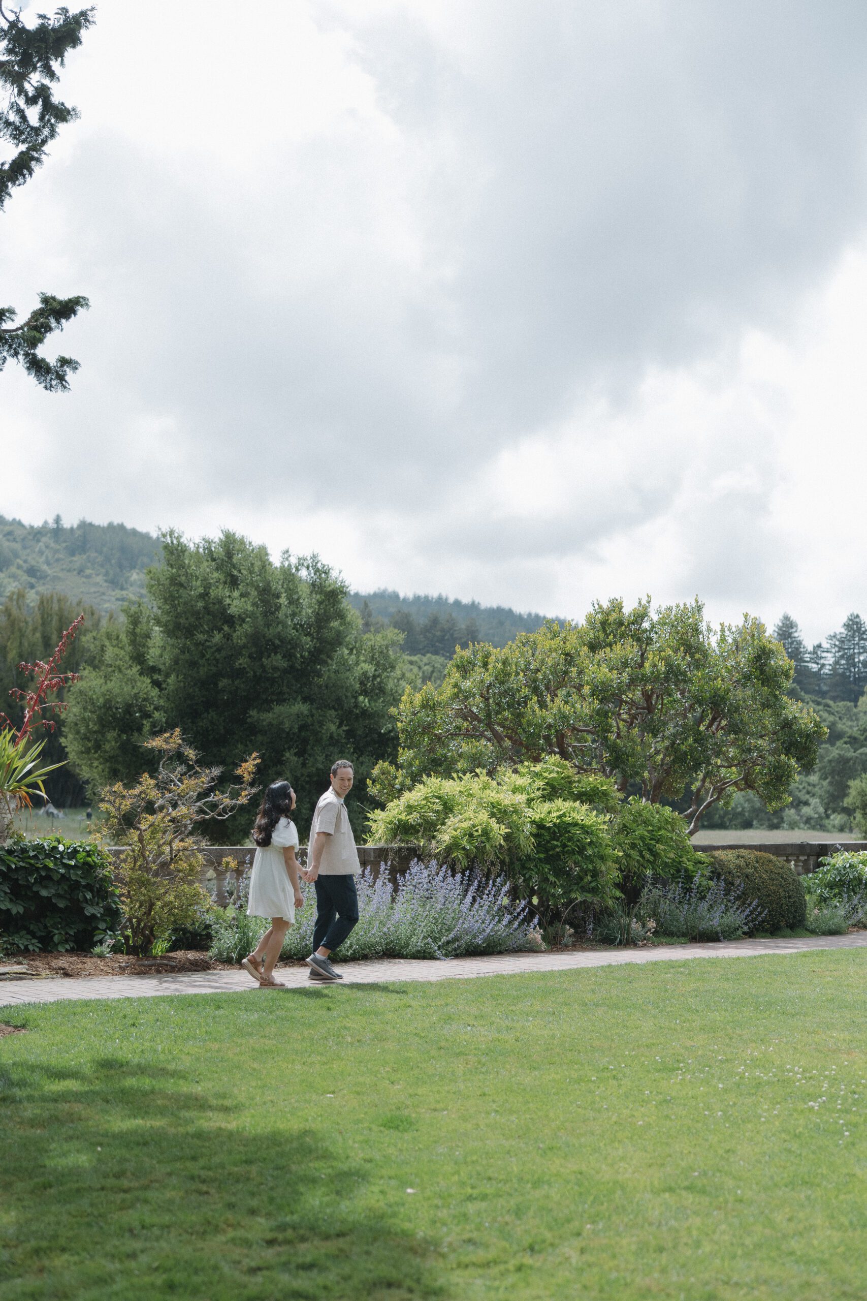 Couple holding hands walking through garden during Northern California engagement photoshoot