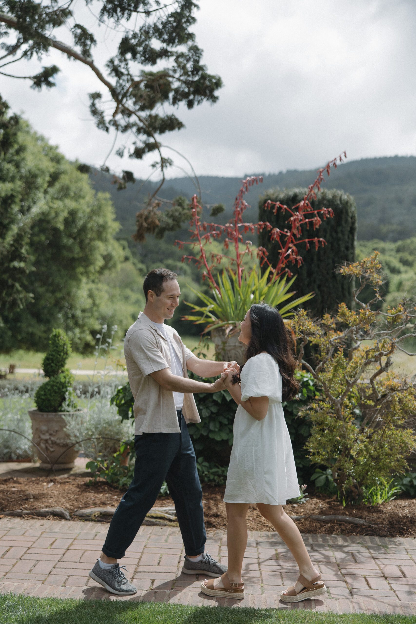 Couple facing each other holding hands in garden engagement photos
