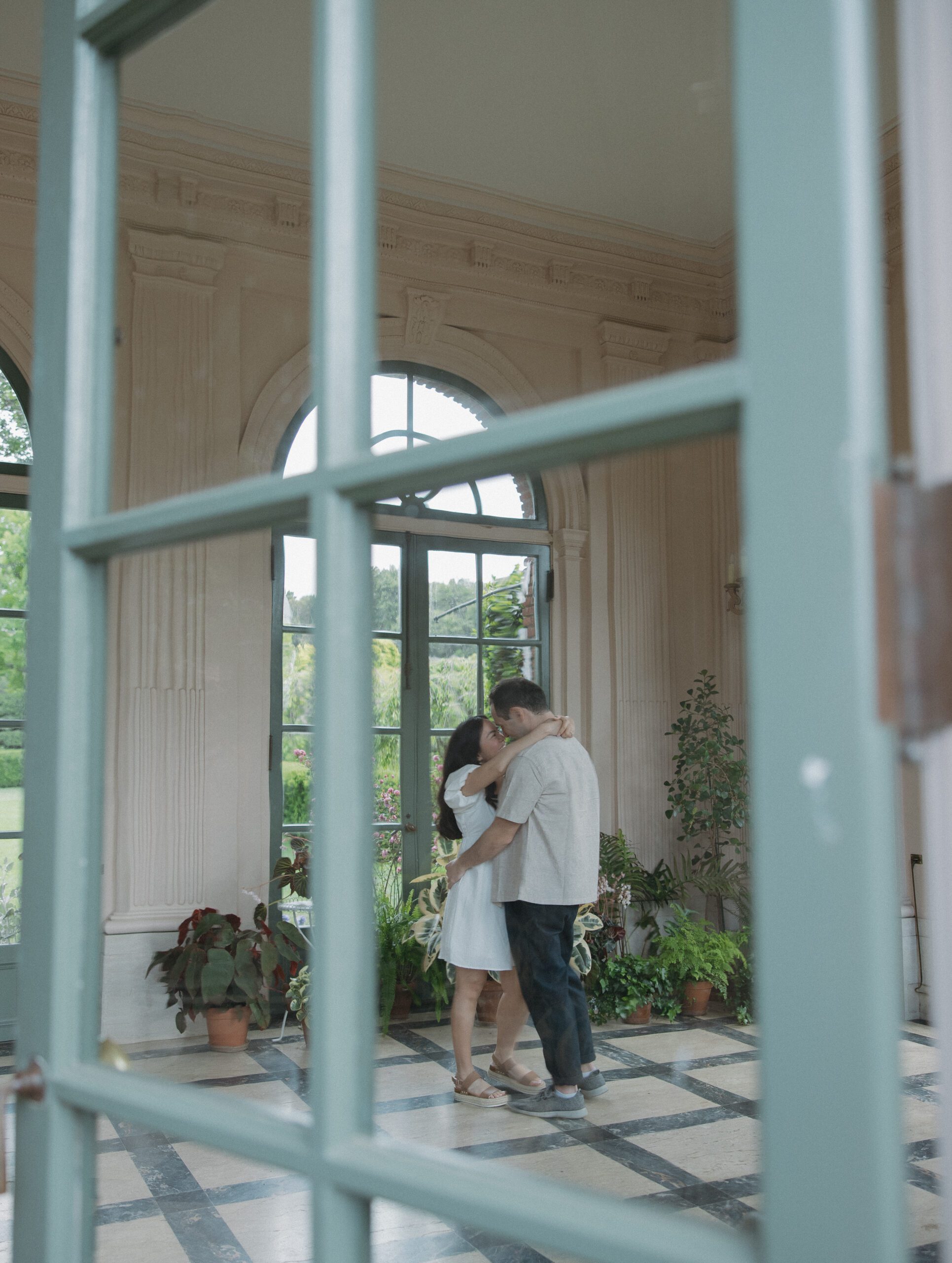 Photo of couple kissing in sunroom taken through window