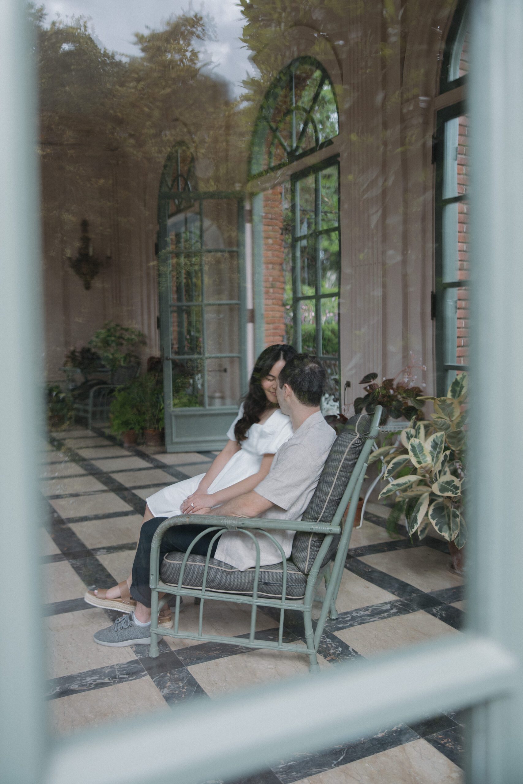Couple sitting in rocking chair with editorial engagement photo taken through the window