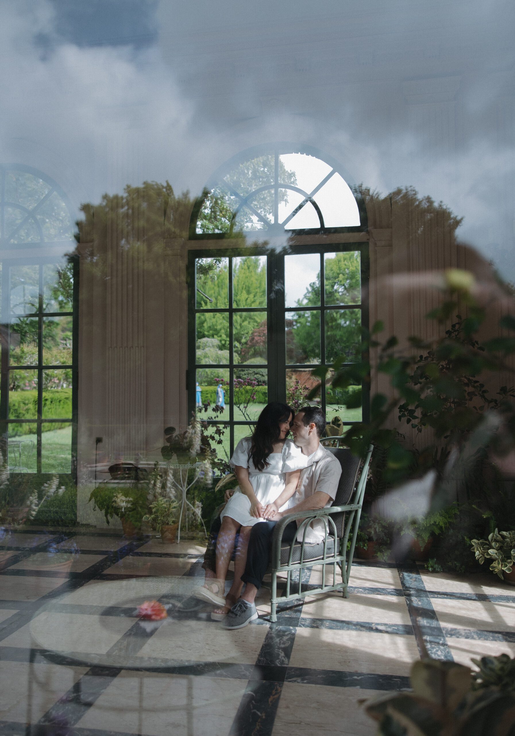 Editorial engagement photo taken through window in garden sunroom