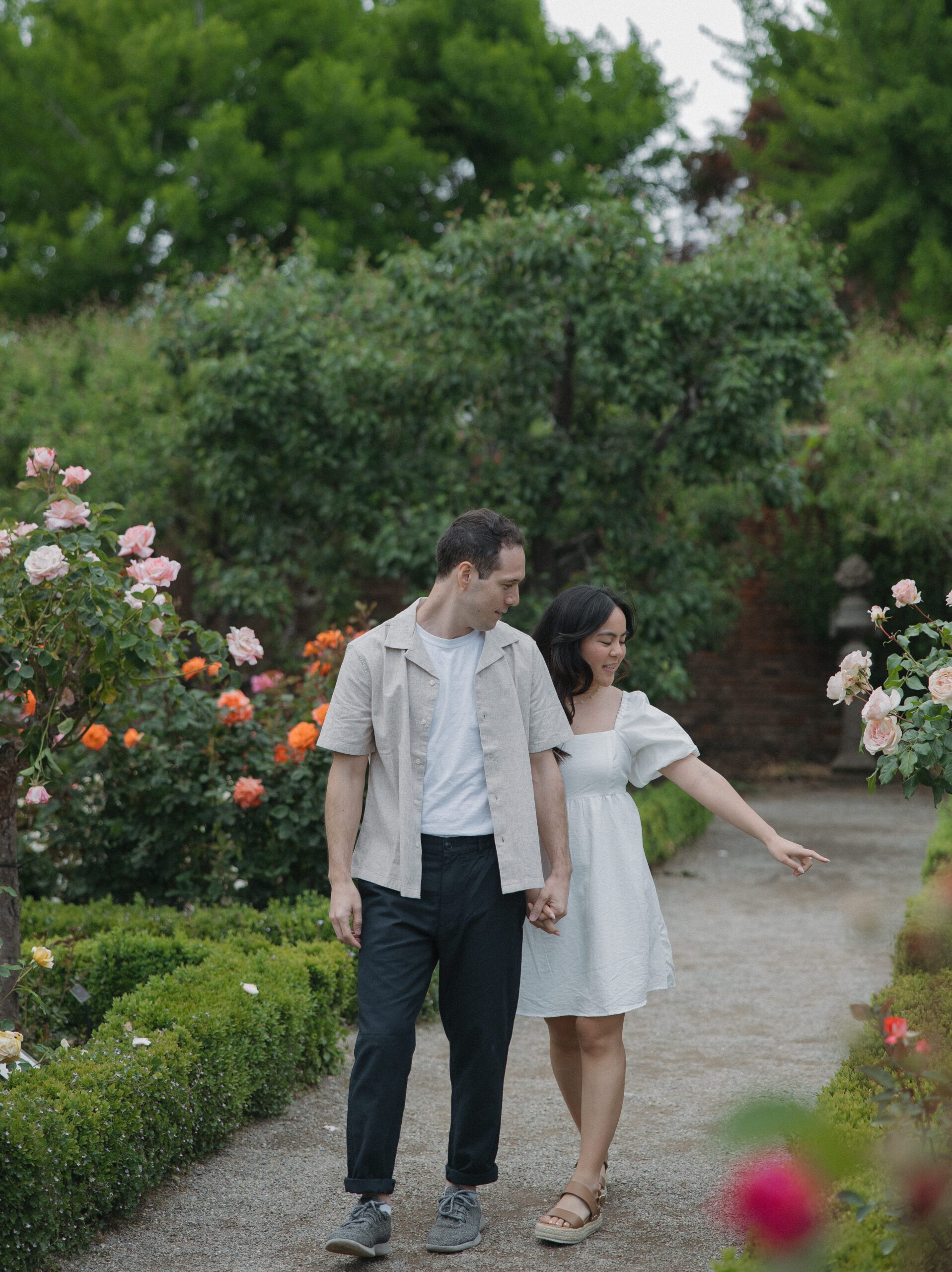 Couple pointing at flowers during garden engagement photos