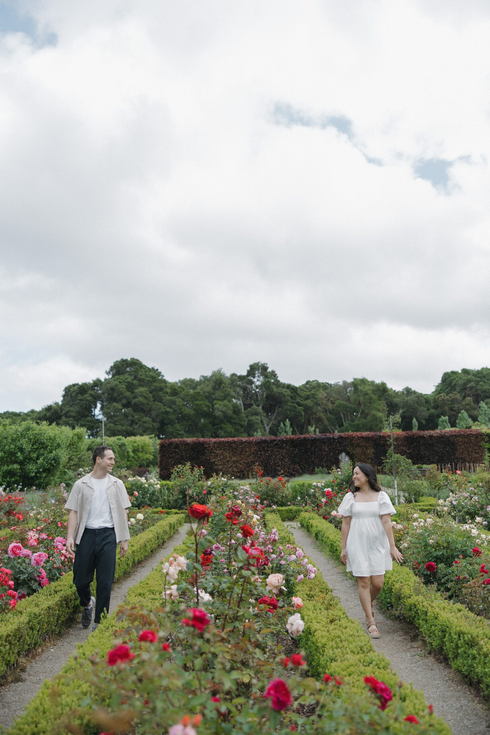 Couple smiling at each other walking through gardens