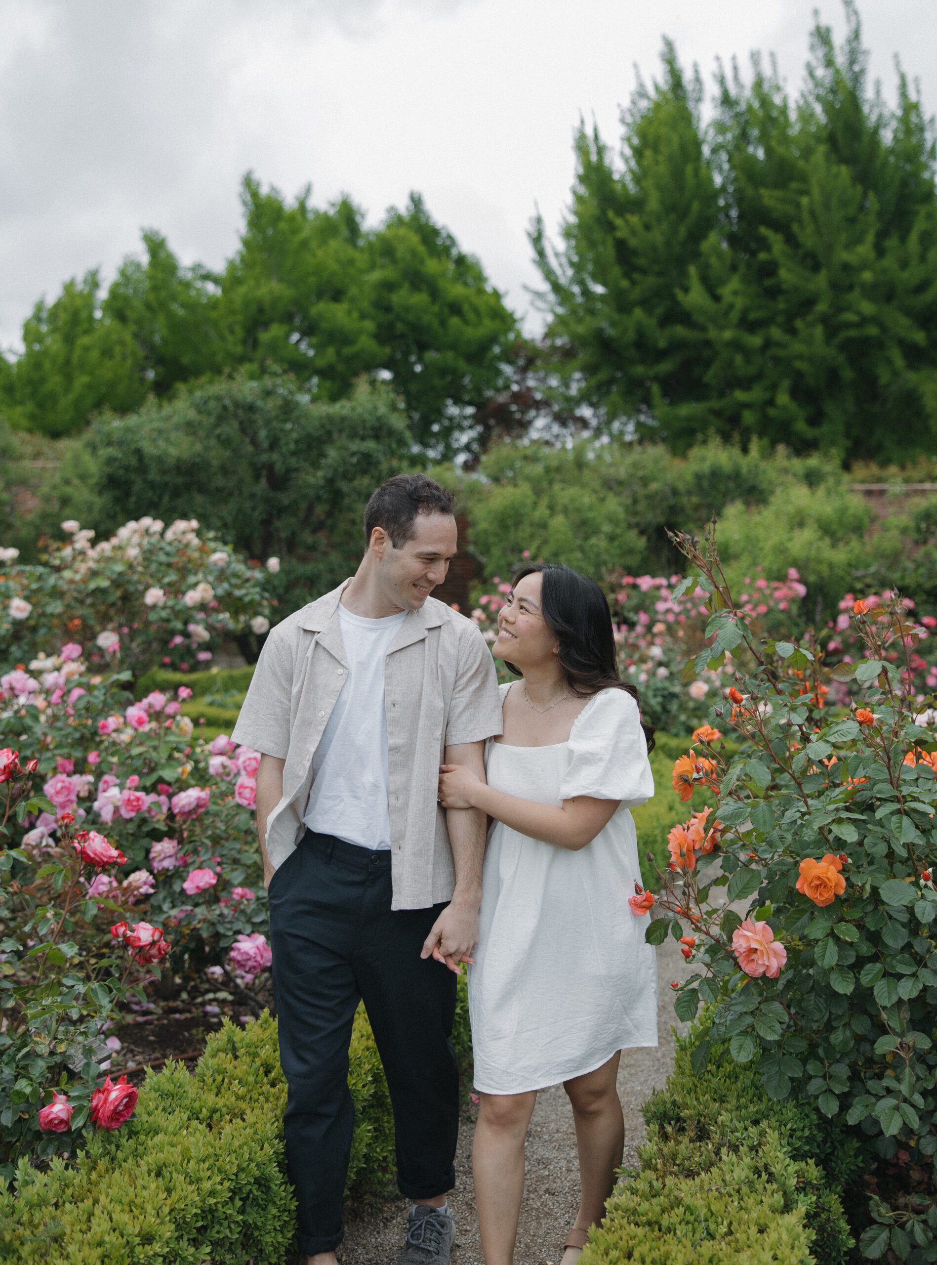 Couple smiling at each other walking through gardens