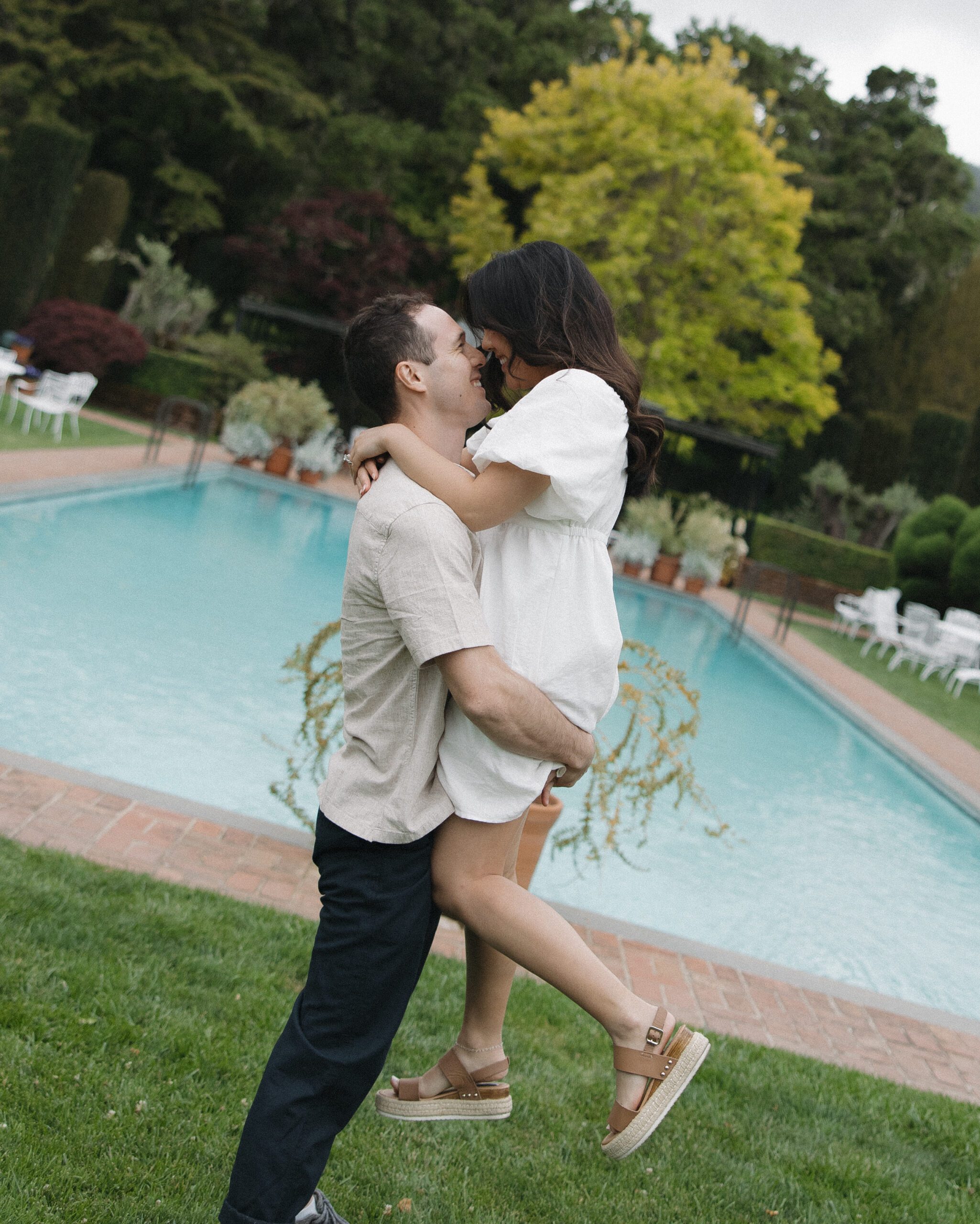 Engagement photo in front of pool with man holding his fiancee