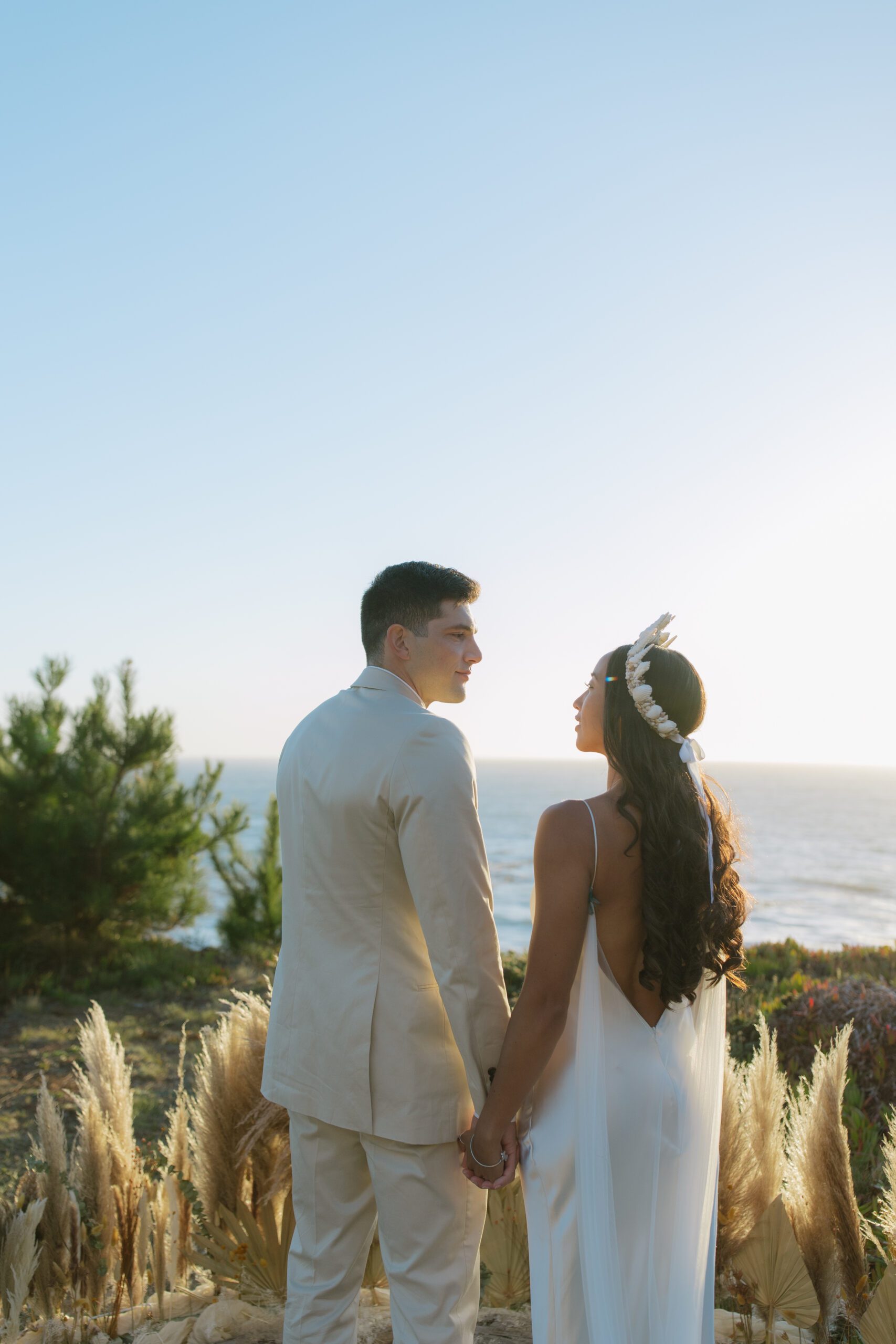 Bride and groom romantic photo looking at each other with the ocean behind them from Bay Area wedding
