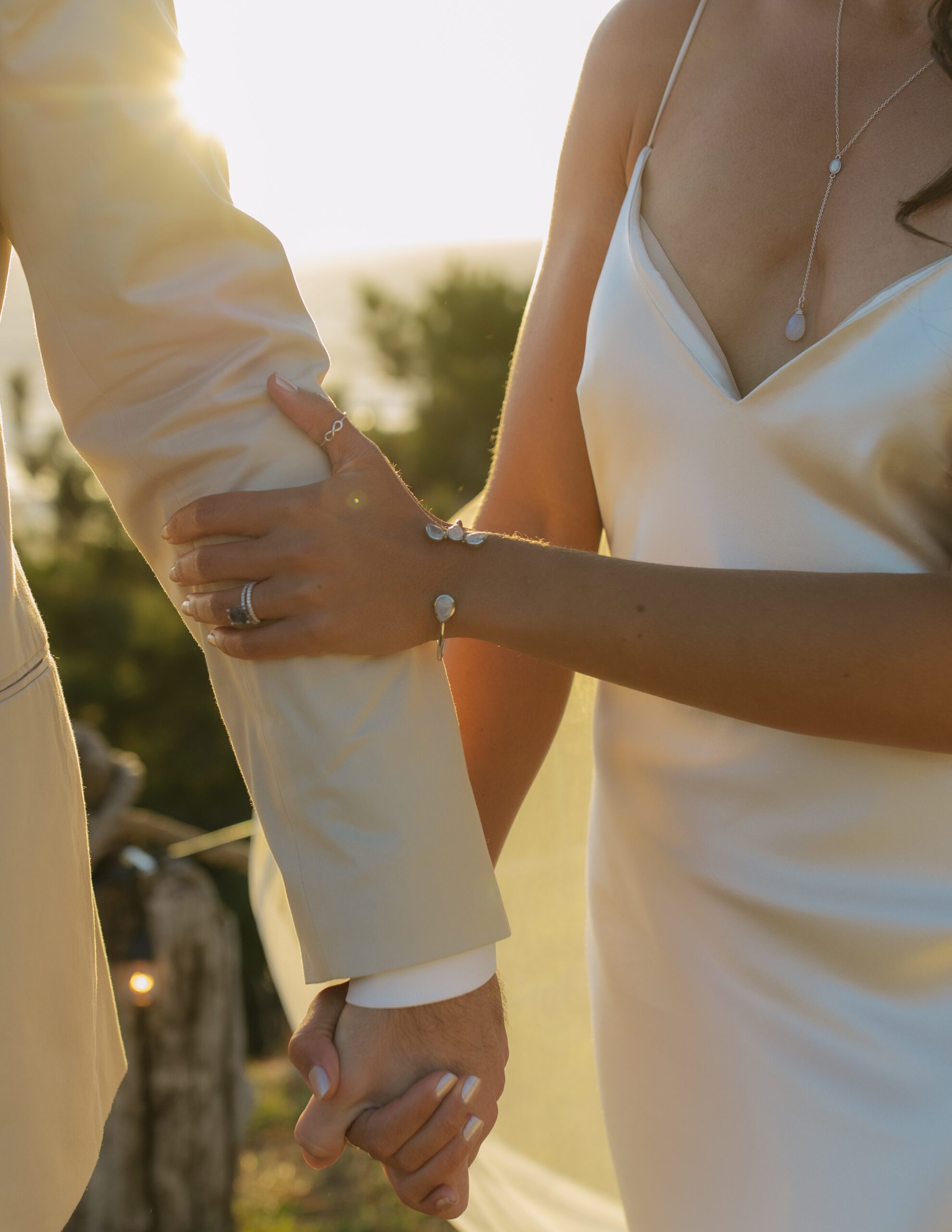 Editorial bride and groom photo of bride holding groom's arm with sun hitting behind them