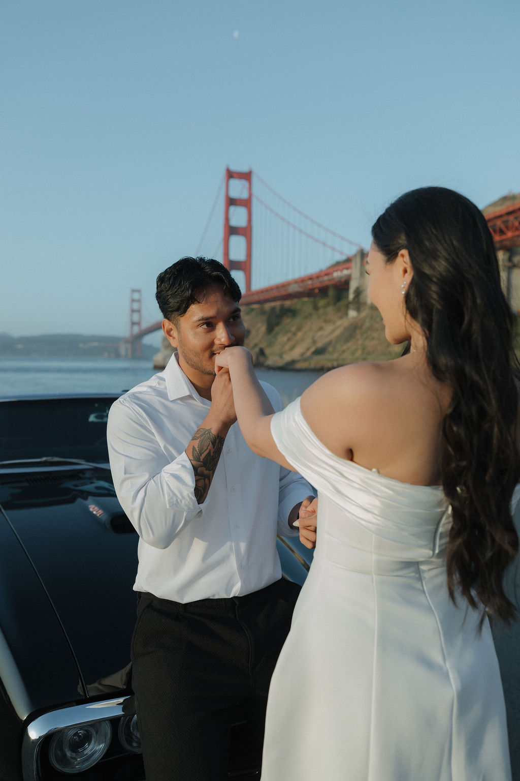 Groom kissing brides hand during Golden Gate Bridge photoshoot
