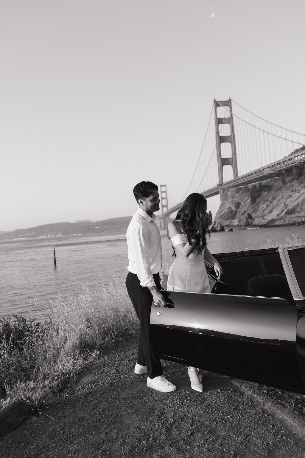 Man holding the door open for his fiancee at Golden Gate Bridge engagement photos