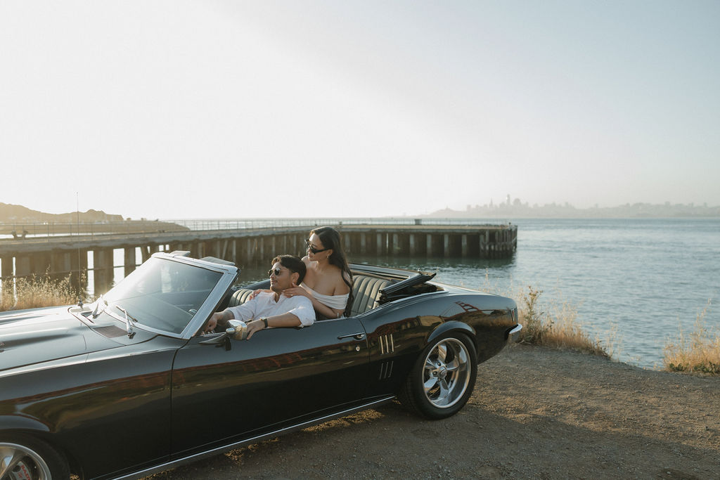 Bride and groom riding in classic car for engagement photos