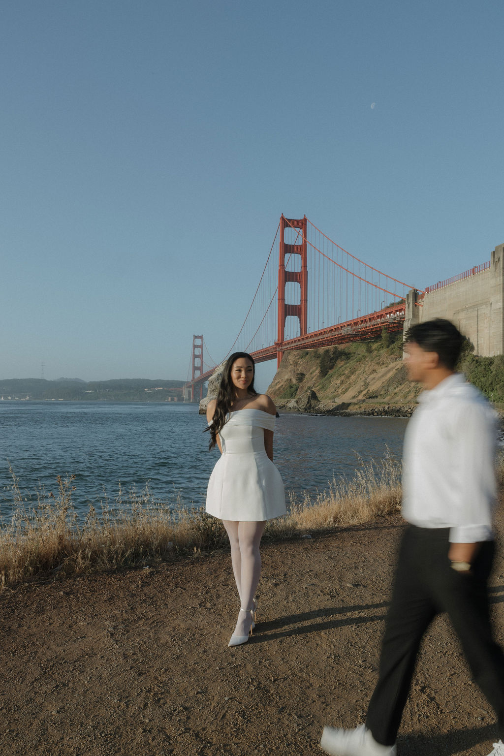 Groom walking around bride during Golden Gate Bridge engagement photos