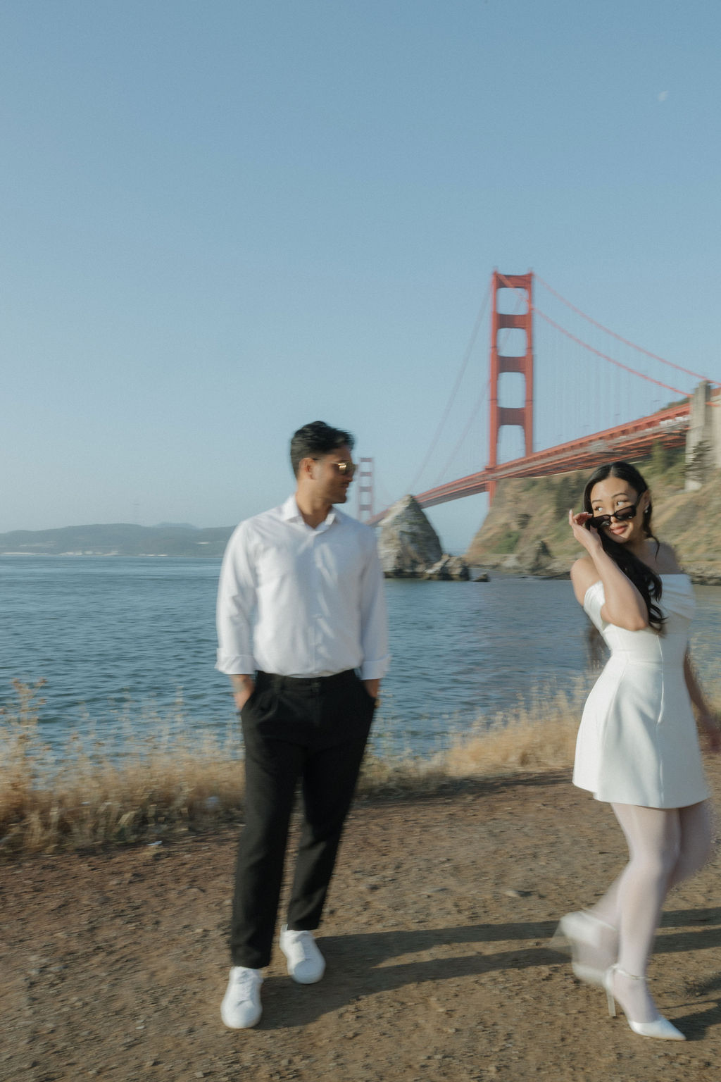 Bride walking around groom during Golden Gate Bridge engagement photos