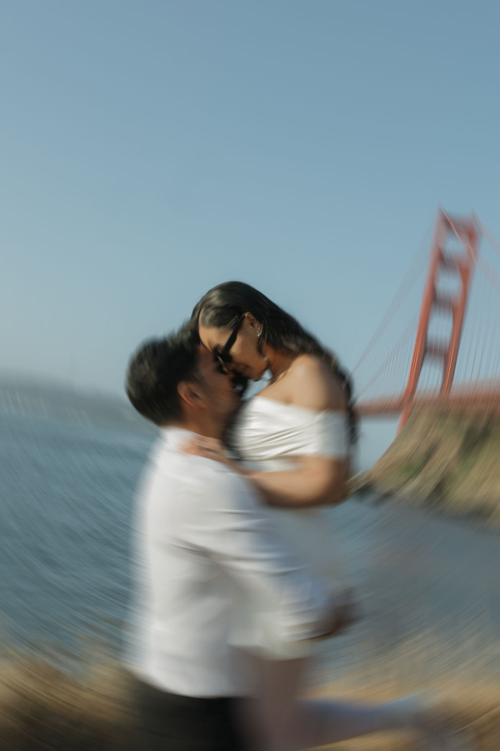 Blurry engagement photo at Golden Gate Bridge engagement photoshoot of groom holding bride
