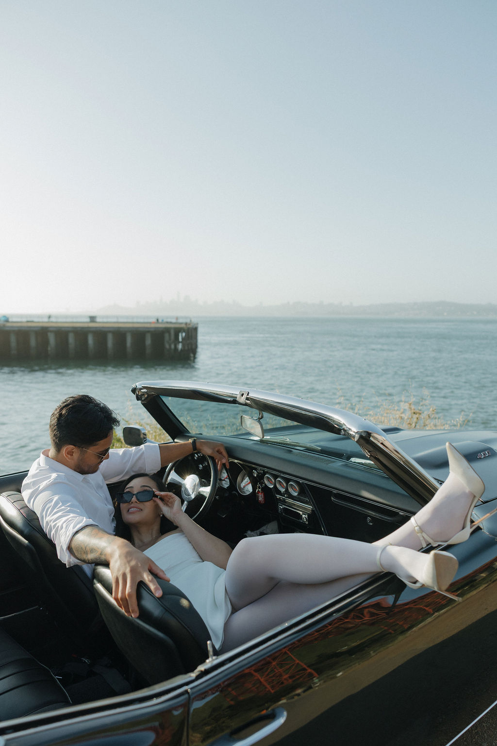 Editorial engagement photos with a classic car with bride laying down kicking her feet up out of convertible
