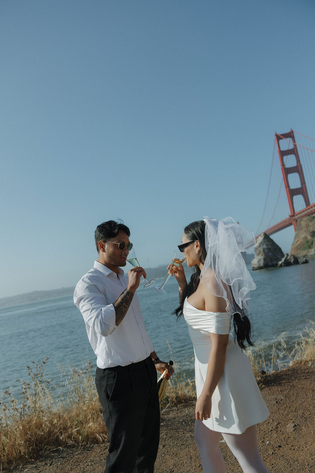 Couple drinking champagne during Golden Gate Bridge engagement photos
