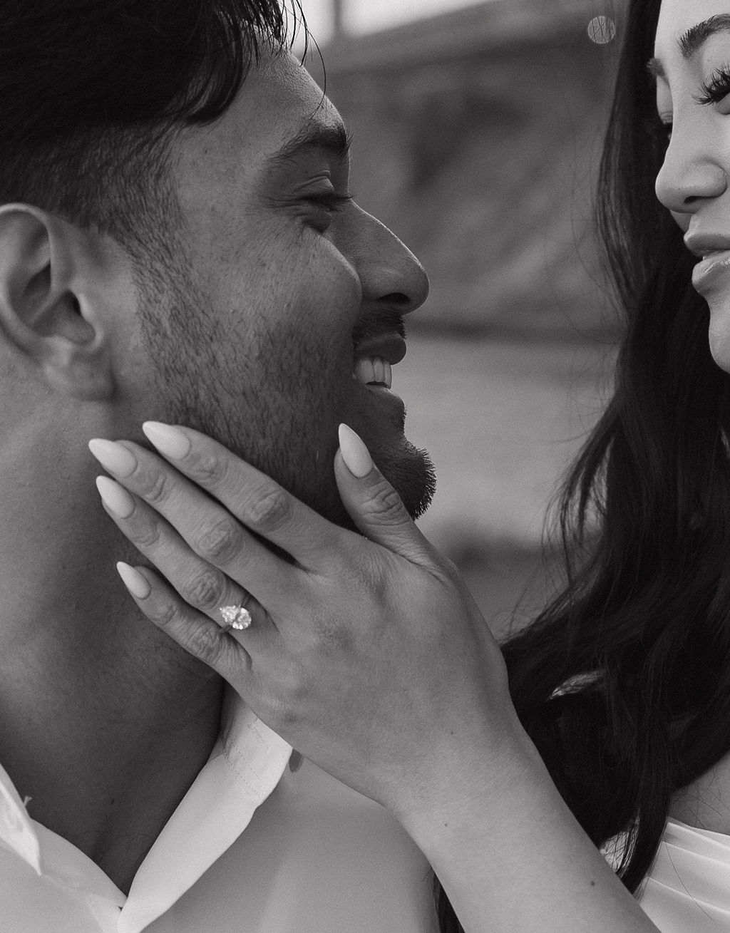 Up close engagement photo of bride holding groom's face and showing off engagement ring