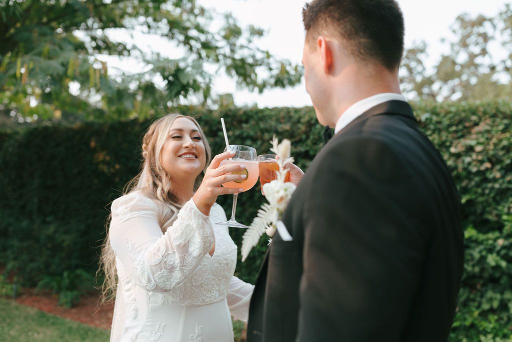 Bride and groom clinking glasses at their outdoor California wedding reception