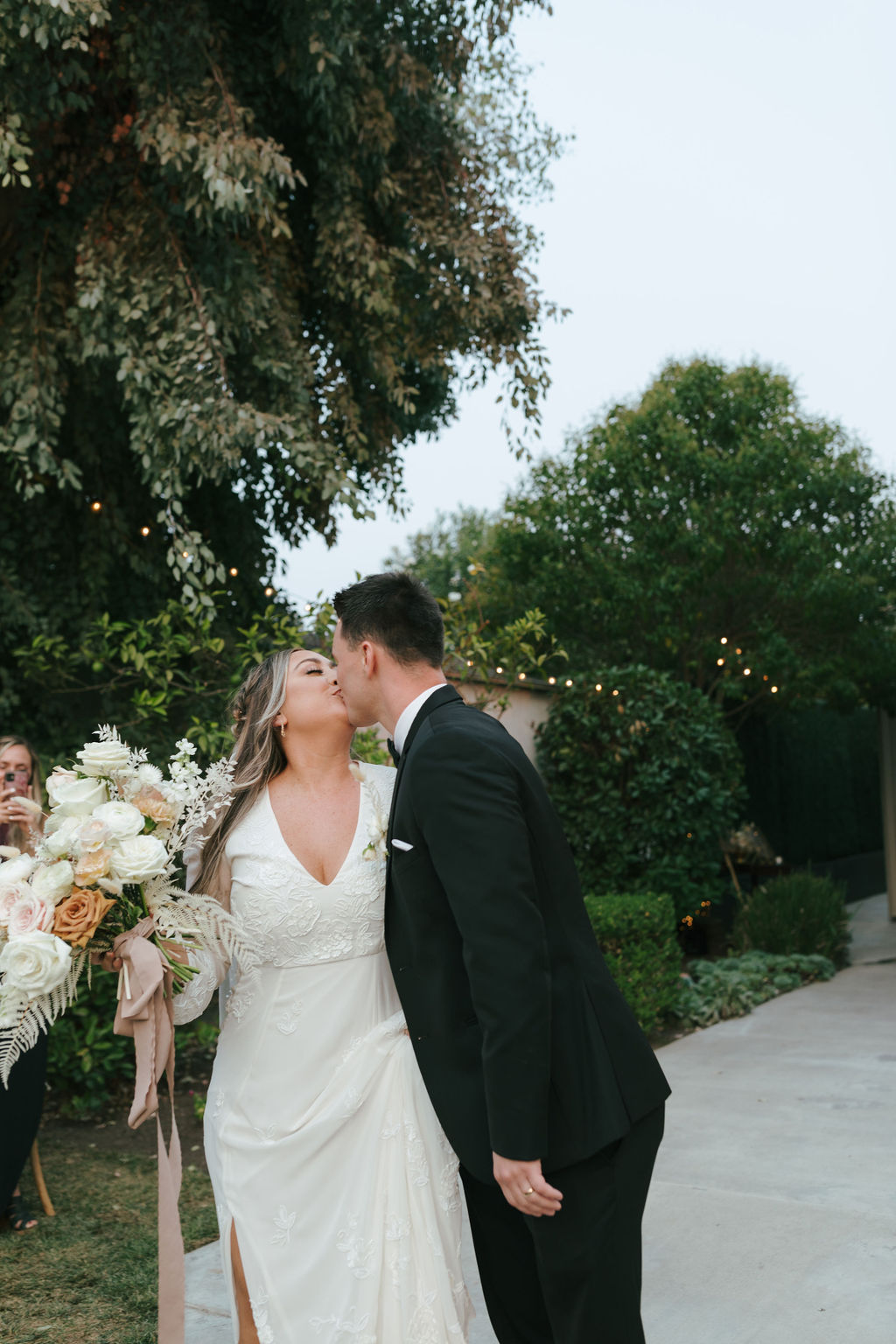 Bride and groom kissing while walking away from wedding ceremony