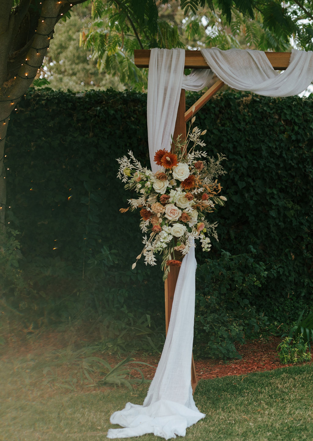 Burnt orange and white wedding florals on wedding arch during nontraditional wedding ceremony